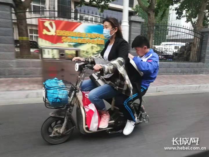 石家庄,一名中考生坐在电动车的后座上仍在看书.